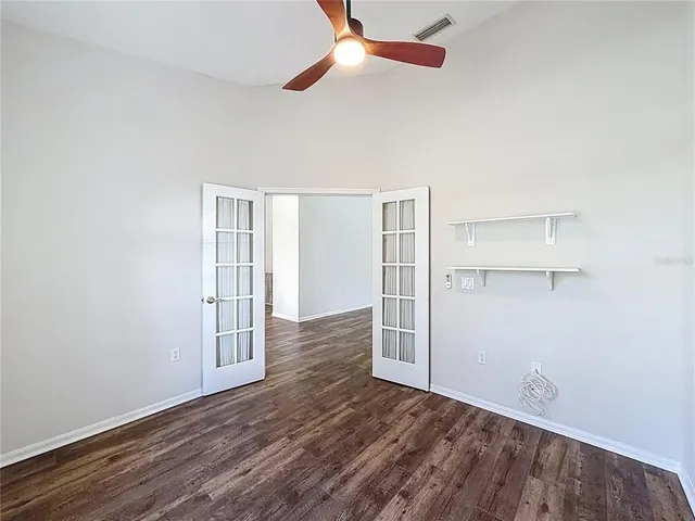 an empty room with wooden floor closet and windows