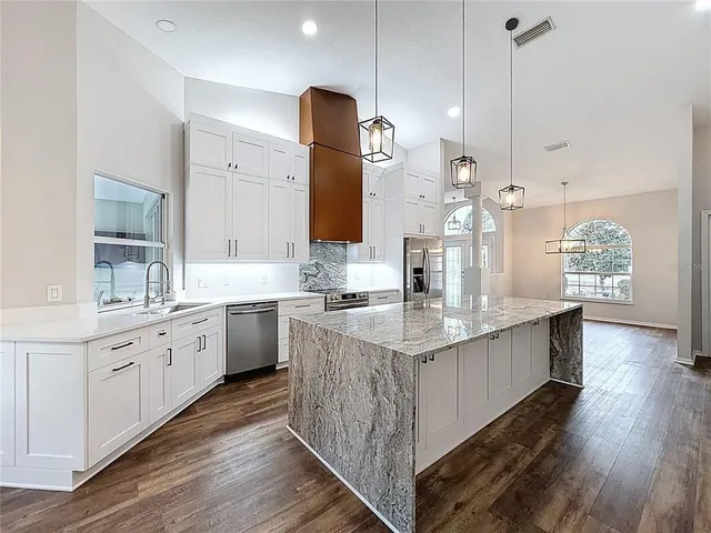 a kitchen with kitchen island granite countertop a sink appliances and cabinets