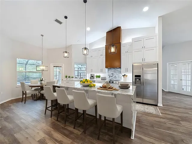 a kitchen with stainless steel appliances granite countertop a kitchen island a table and chairs