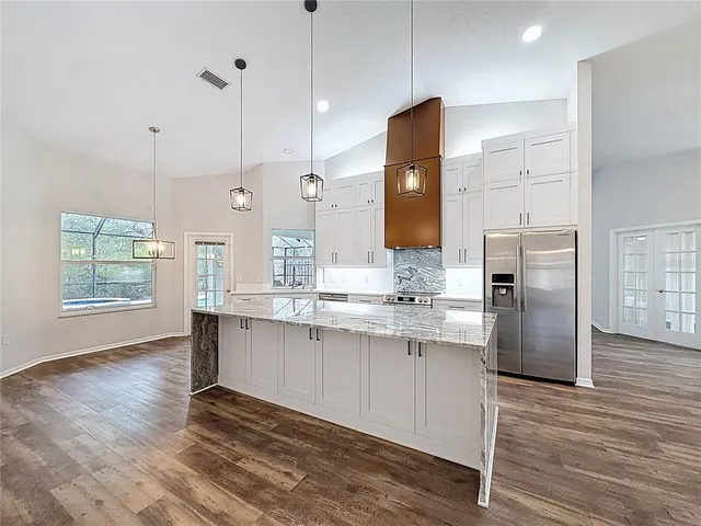 a large kitchen with granite countertop a large counter top a sink stainless steel appliances and cabinets