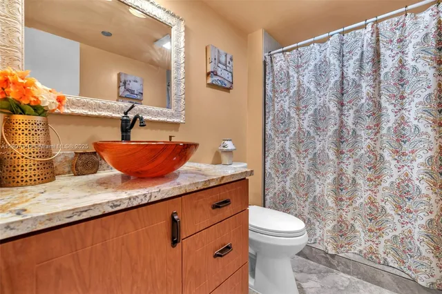 a bathroom with a granite countertop sink a toilet and a shower