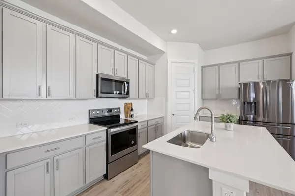 a kitchen with a sink white cabinets and stainless steel appliances