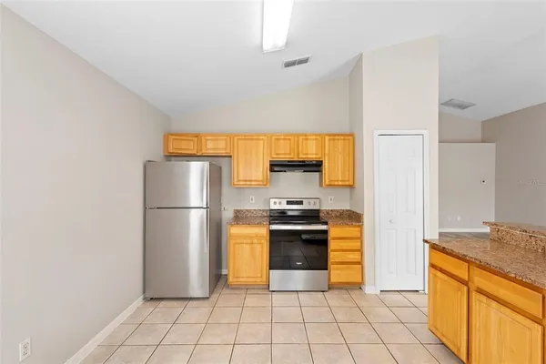 a kitchen with granite countertop a refrigerator and a stove top oven