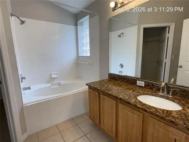 a bathroom with a granite countertop sink mirror and a bathtub