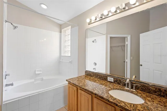 a bathroom with a granite countertop sink tub double vanity and a mirror