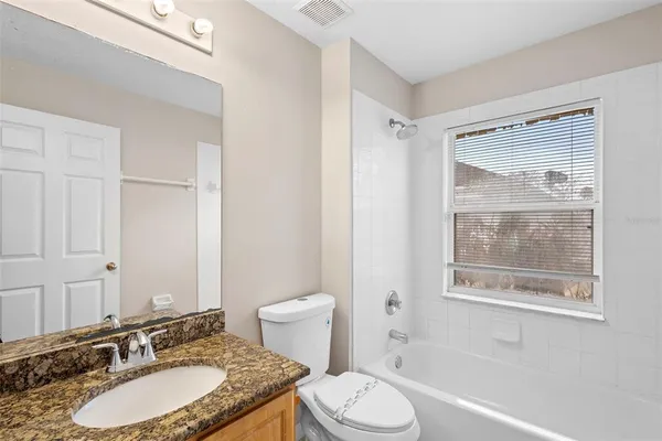 a bathroom with a granite countertop sink toilet a mirror and shower
