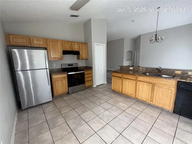 a kitchen with granite countertop a refrigerator and a stove top oven