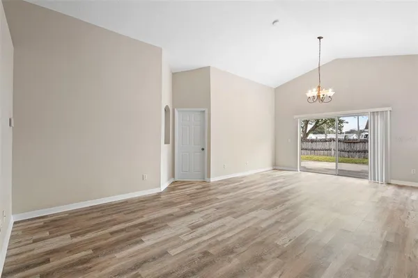 a view of an empty room with window and wooden floor
