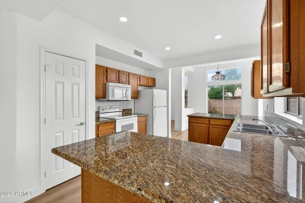 a view of a kitchen with stainless steel appliances granite countertop a refrigerator a sink and wooden floors