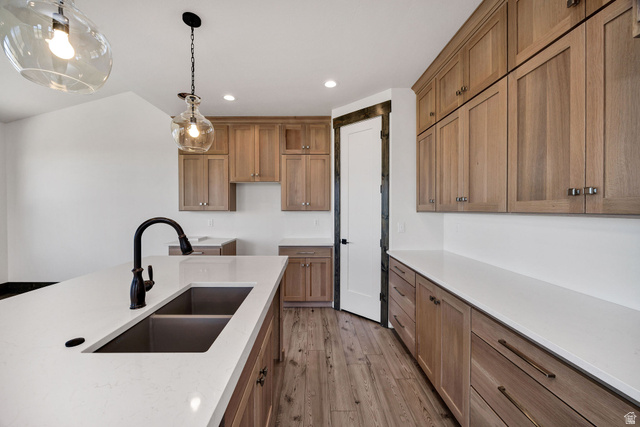 300 Knoll Loop, Unit 227 Fish Haven, ID 83287 - Photo 11 of 56 Kitchen featuring wood finish cabinets, hanging light fixtures, light stone countertops, and light wood-type flooring