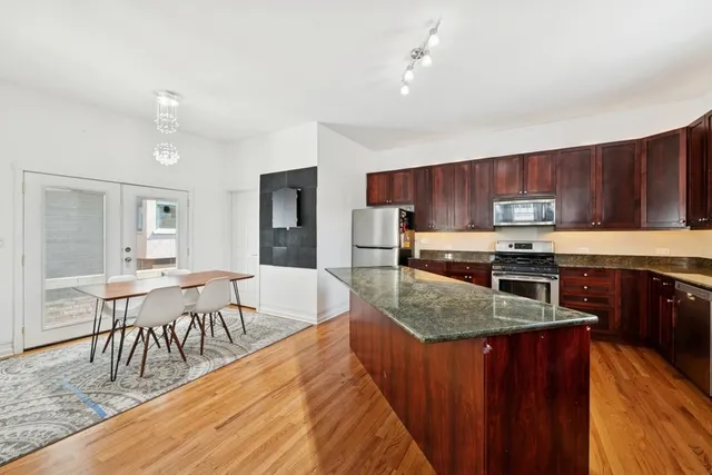 a kitchen with stainless steel appliances granite countertop wooden cabinets a dining table and chairs