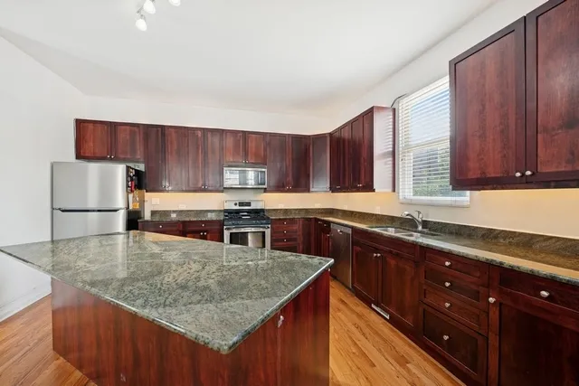 a kitchen with stainless steel appliances granite countertop a sink a microwave and wooden cabinets