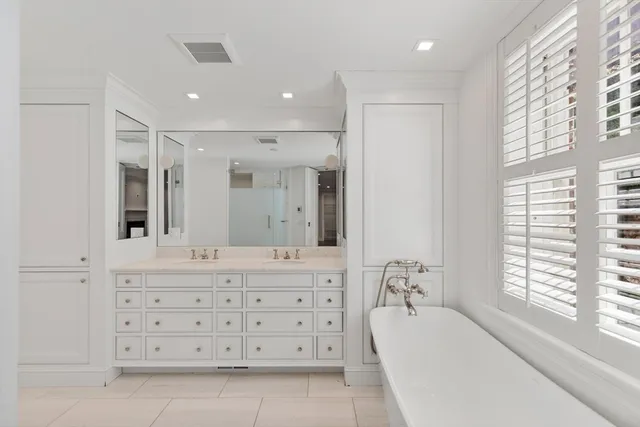 a bathroom with a granite countertop sink mirror bathtub and next to a window