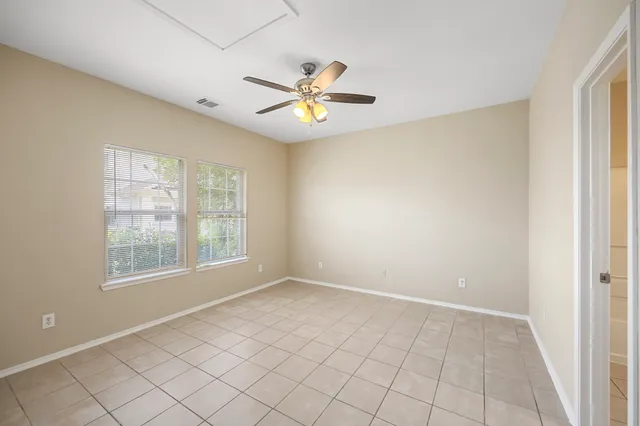 a view of an empty room with window and chandelier fan