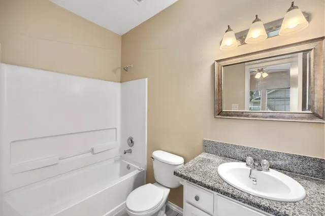 a bathroom with a granite countertop sink toilet a mirror and bathtub