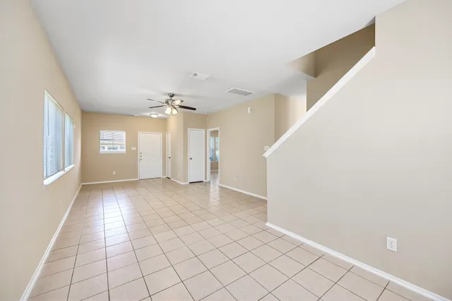 a view of an empty room with window and chandelier fan