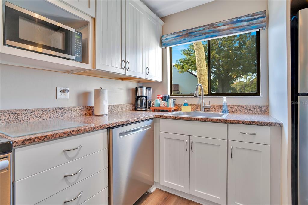 1646 Stickney Point Road, Unit 1646101 Sarasota, FL 34231 - Photo 14 of 67 a kitchen with granite countertop white cabinets and window