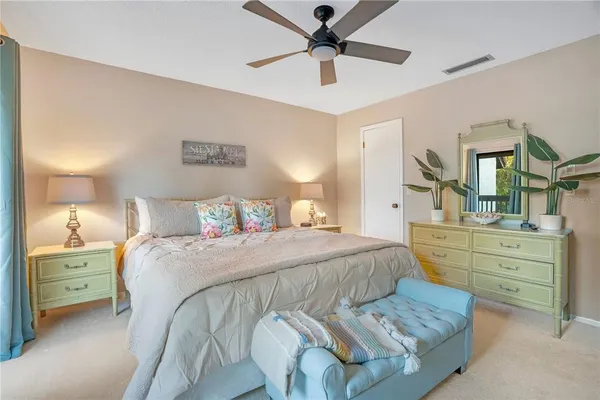 a spacious bedroom with a bed and a lamp on dresser