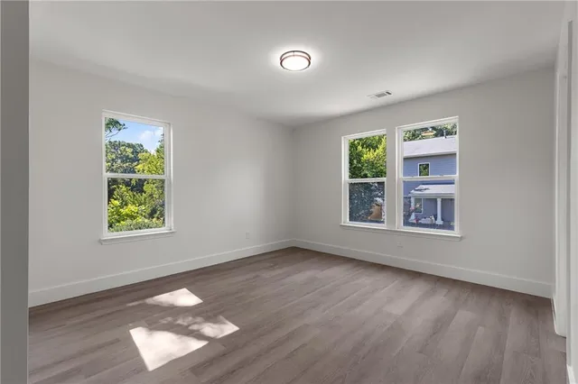 an empty room with wooden floor and windows