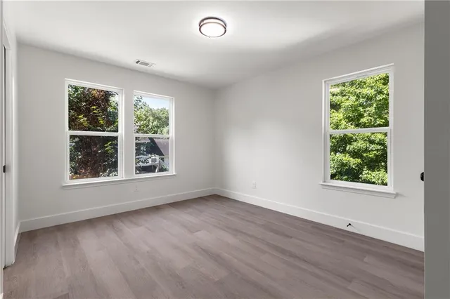 an empty room with wooden floor and windows