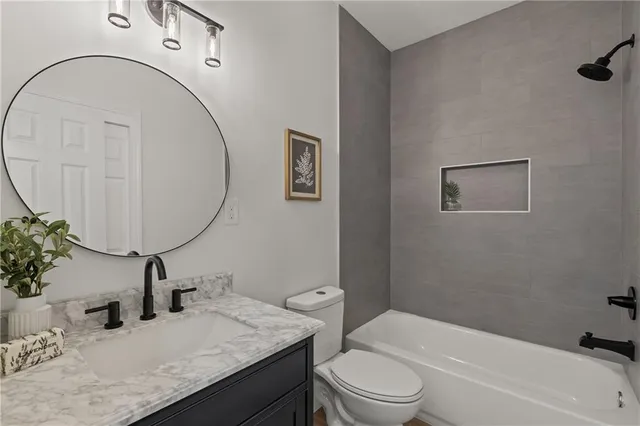 a bathroom with a granite countertop sink mirror vanity and toilet