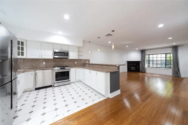 a large kitchen with stainless steel appliances a large counter top a stove a sink a refrigerator and cabinets