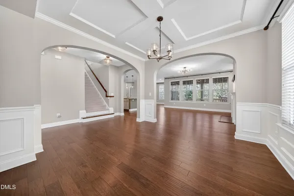 a view of an empty room with wooden floor fan and windows