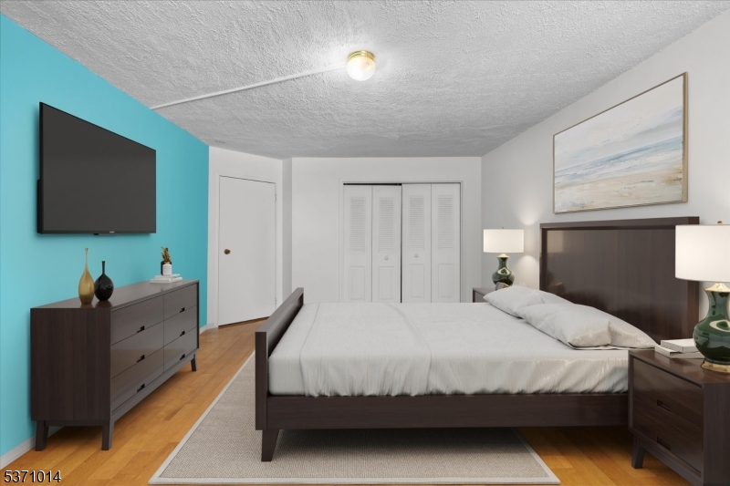 401 Harmon Cove Tower Secaucus, NJ 07094 - Photo 26 of 47 a bedroom with a bed and a flat tv screen on dresser