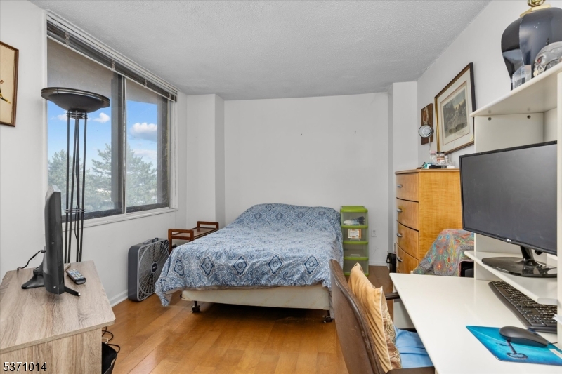 401 Harmon Cove Tower Secaucus, NJ 07094 - Photo 27 of 47 a bedroom with a bed and a dresser next to a window