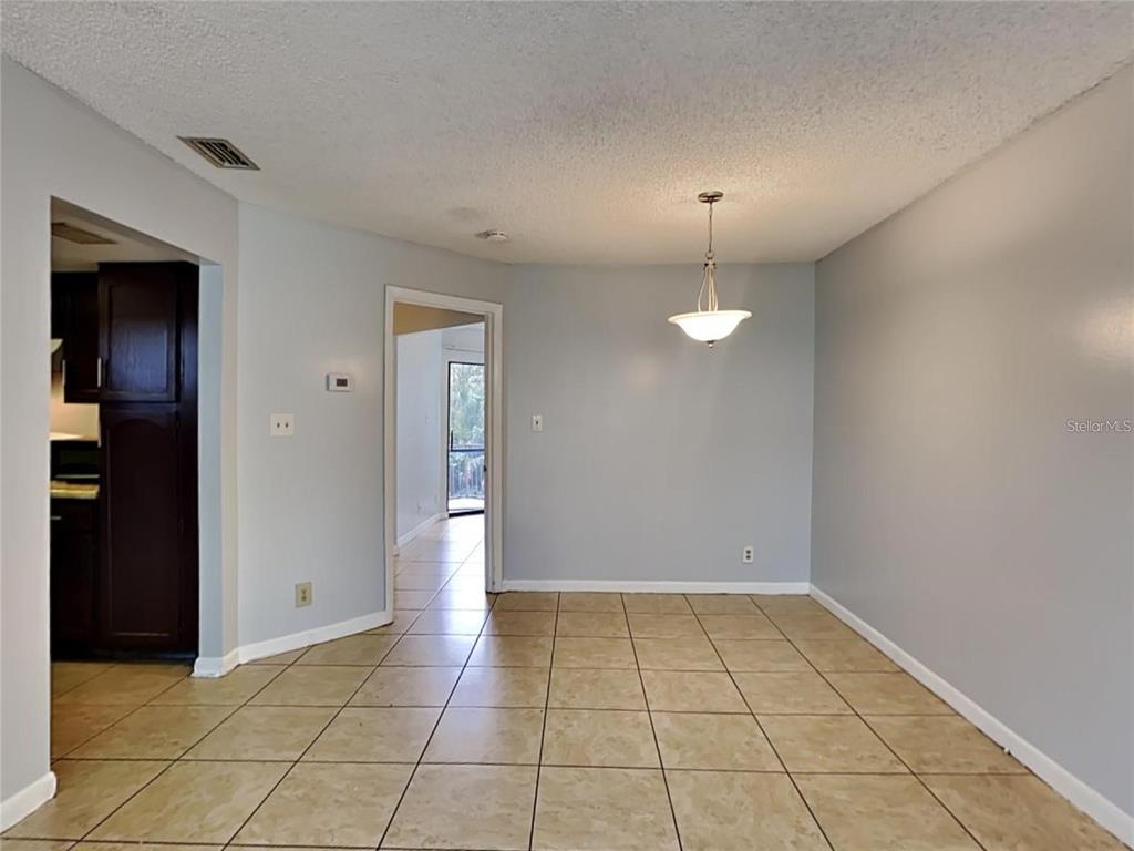 2546 Lemon Tree Lane, Unit G Orlando, FL 32839 - Photo 24 of 28 an empty room with wooden floor and chandelier