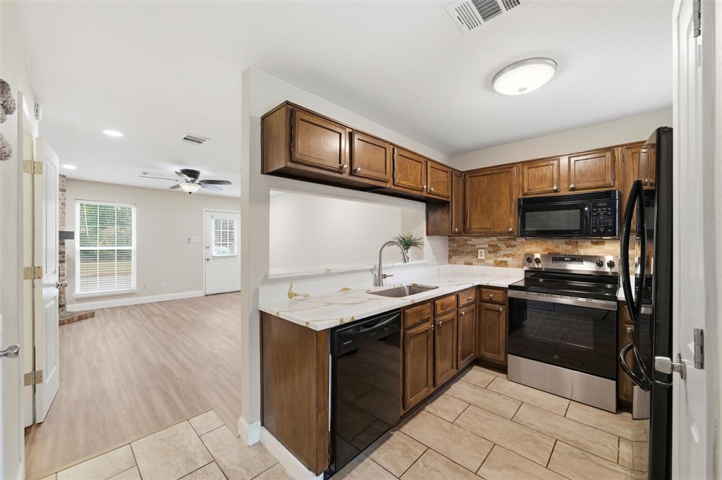 112 Churchill Lane Euless, TX 76039 - Photo 8 of 33 a kitchen with stainless steel appliances granite countertop a sink and stove top oven with wooden floor