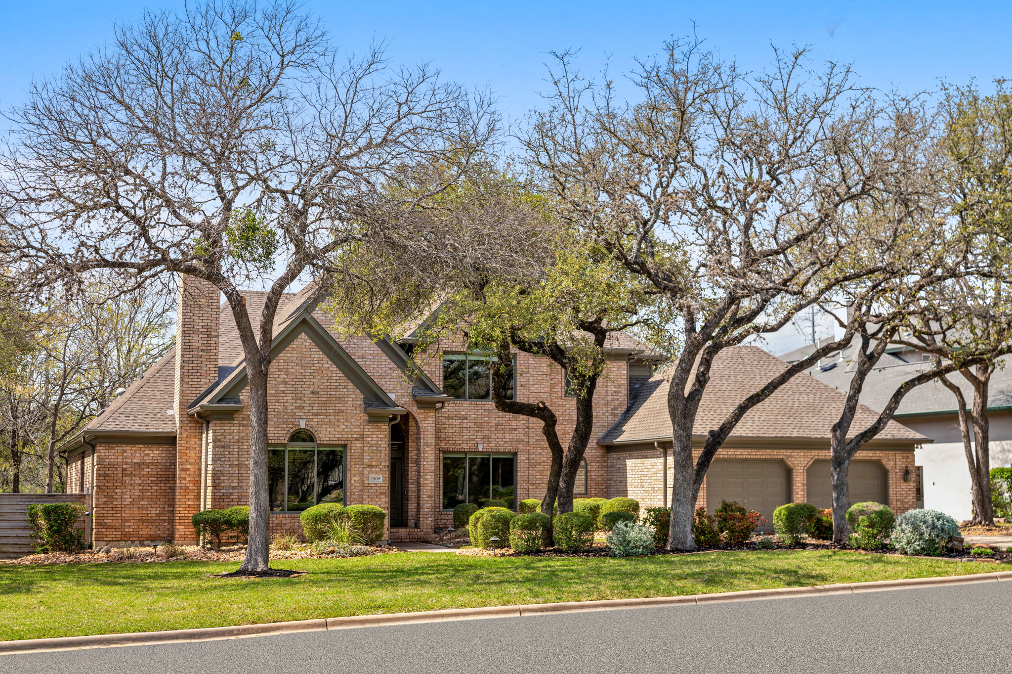 Traditional-style home with brick siding, a front lawn, an attached garage, and a chimney in Parkstone Westlake