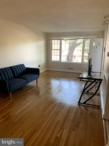a living room with a couch wooden floor and a large window