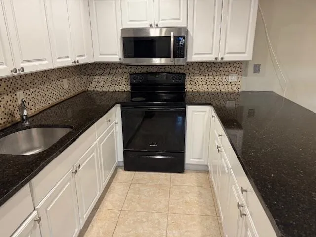a kitchen with granite countertop white cabinets and black appliances