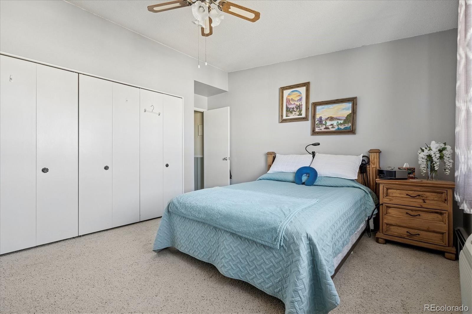 660 South Alton Way, Unit 2D Denver, CO 80247 - Photo 12 of 32 a spacious bedroom with a bed and a chandelier