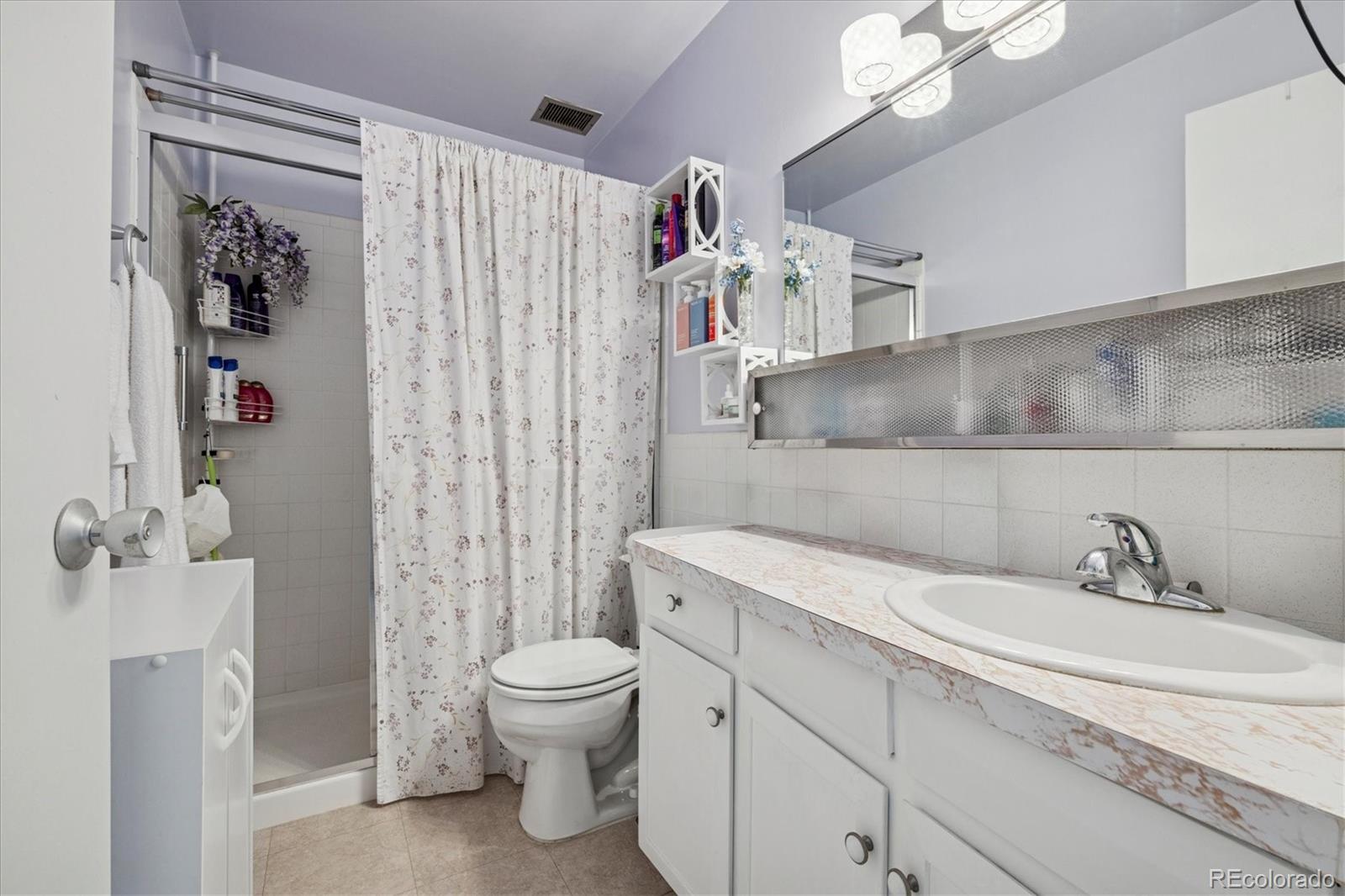 660 South Alton Way, Unit 2D Denver, CO 80247 - Photo 9 of 32 a bathroom with a sink a toilet and shower curtain