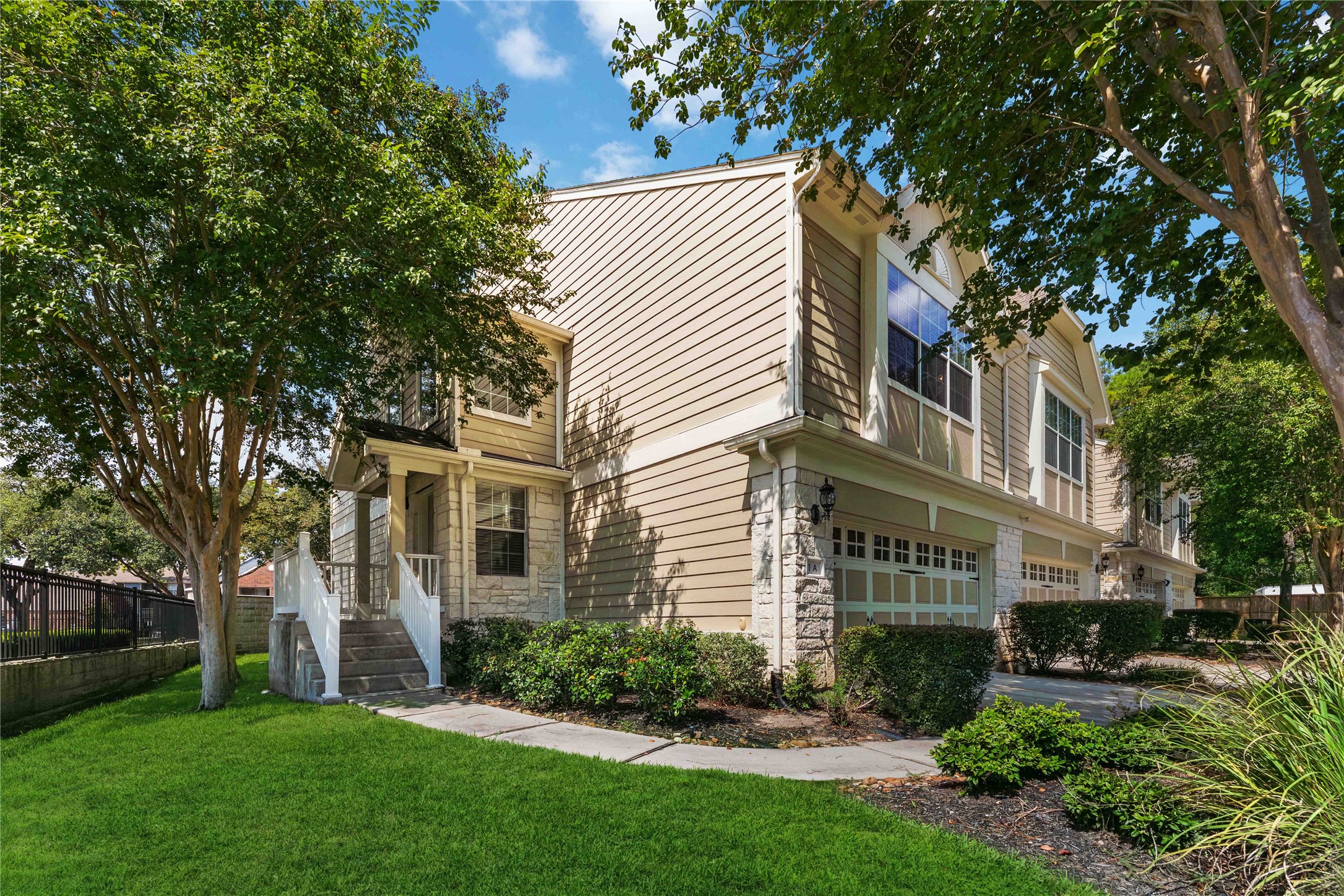 a view of a white house next to a yard with big trees