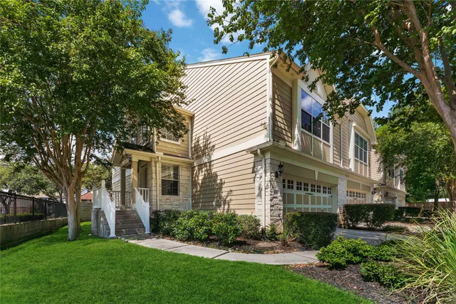 a view of a white house next to a yard with big trees