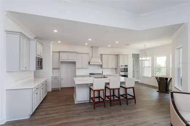 a large kitchen with kitchen island a dining table chairs and white cabinets
