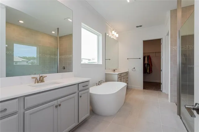 a spacious bathroom with a double vanity sink a mirror and a bathtub