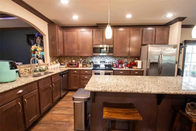 a kitchen with kitchen island granite countertop wooden cabinets a refrigerator and a sink