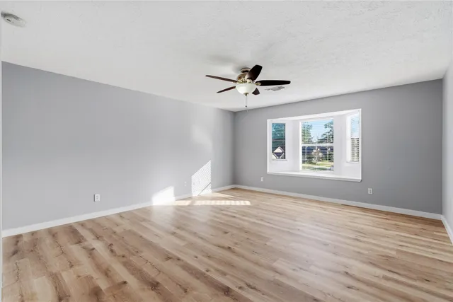 a view of an empty room with a window and wooden floor