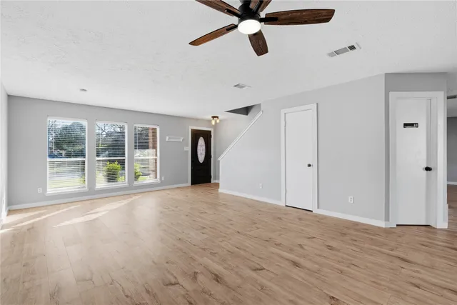 a view of an empty room with a window and wooden floor