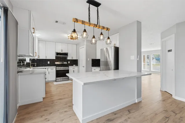 a kitchen with white cabinets and refrigerator