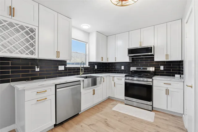 a kitchen with stainless steel appliances granite countertop a stove a sink and white cabinets