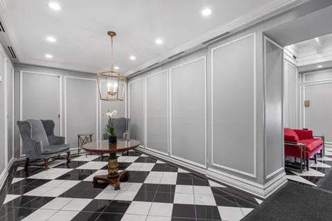 a room with black white checkered floor furniture a rug and a window