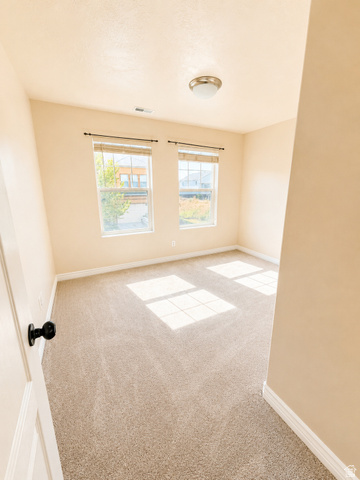 14767 Invergarry Court Draper, UT 84020 - Photo 11 of 18 Room featuring neutral-toned carpet, two windows with blinds, a flush-mount ceiling light, and light beige wall paint