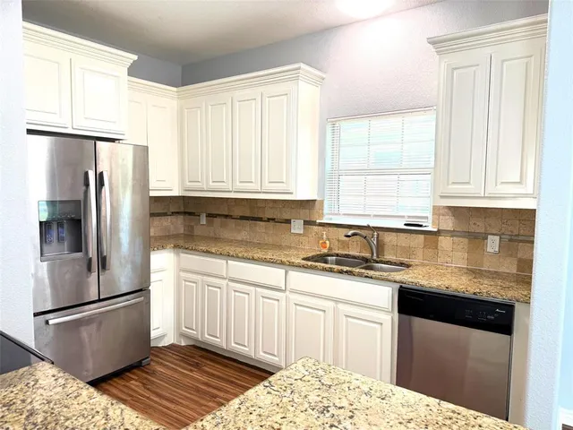 a kitchen with granite countertop a sink stainless steel appliances and cabinets