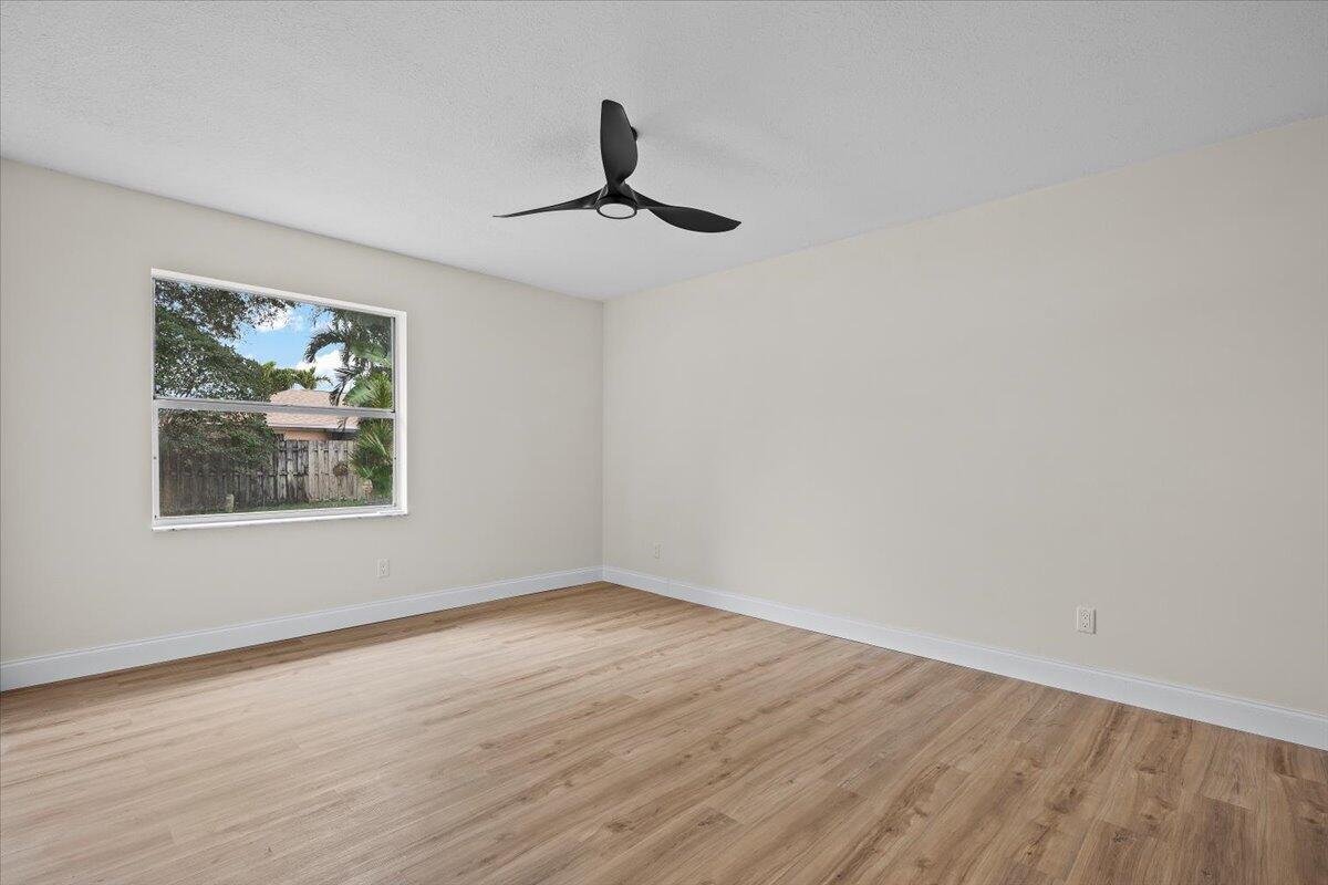 126 Wandering Trail Jupiter, FL 33458 - Photo 13 of 16 a view of an empty room with wooden floor and a window