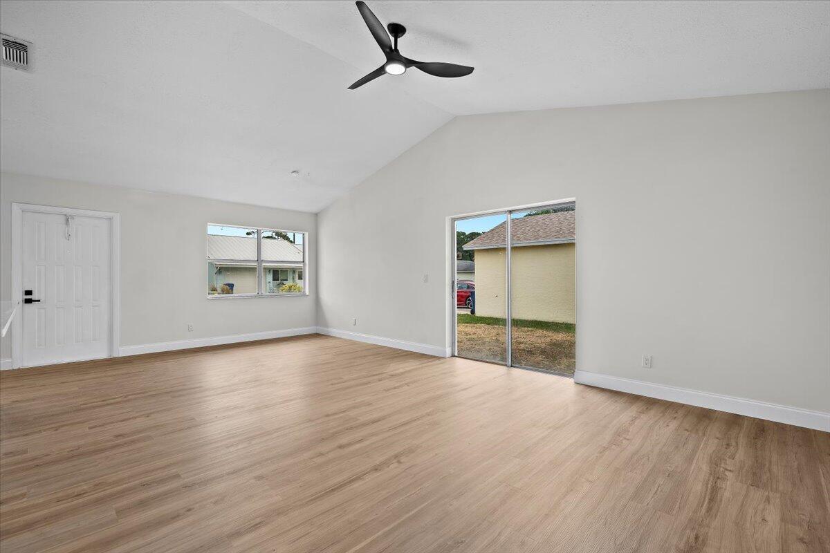126 Wandering Trail Jupiter, FL 33458 - Photo 2 of 16 an empty room with wooden floor cabinet and windows